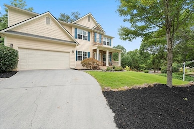 View of front of home with a porch, a front lawn, concrete driveway, and an attached garage