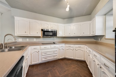 Kitchen with light countertops, a textured ceiling, black appliances, and white cabinets