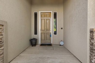 View of exterior entry with stucco siding and a porch