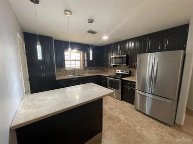 Kitchen with sink, stainless steel appliances, light stone counters, tasteful backsplash, and decorative light fixtures
