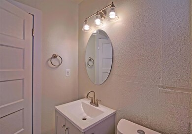 Bathroom featuring a textured wall and vanity