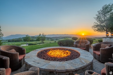 Patio terrace at dusk featuring an outdoor fire pit, a mountain view, and a patio area