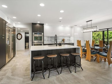 Kitchen with modern cabinets, a sink, double oven, an eat-in island bar, and light countertops