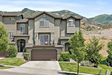 View of front facade with stone siding, a balcony, driveway, stucco siding, and a mountain view