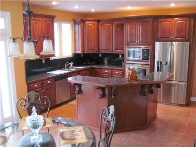 Upscale Gourmet Kitchen with custom cabinets, granite countertops, island with jenn-aire cooktop/ stainless appliances.