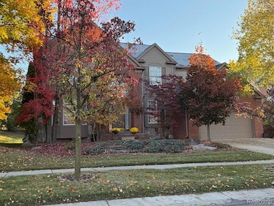 Obstructed view of property featuring a front yard, a garage, brick siding, and driveway