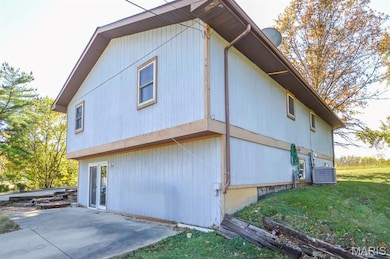 View of side of home featuring a cooling unit and a patio