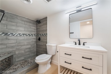 Bathroom featuring vanity, a tile shower, and wood