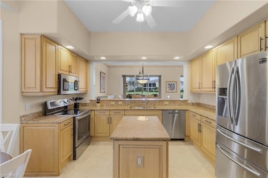 Kitchen featuring stainless steel appliances, recessed lighting, light stone counters, light brown cabinetry, and a kitchen island
