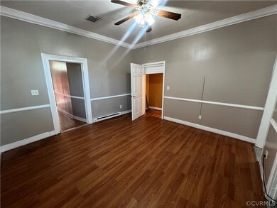 Empty room featuring crown molding, dark wood-type