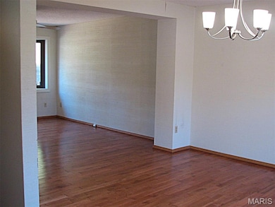 Unfurnished room with dark wood-style floors and a chandelier
