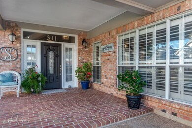 View of exterior entry featuring covered porch and brick siding
