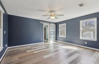 Empty room with a wealth of natural light, visible vents, a ceiling fan, and wood finished floors