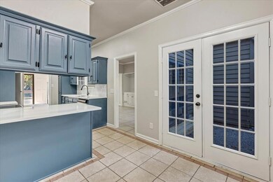 Kitchen featuring blue cabinets, light tile patterned floors, french doors, and crown molding