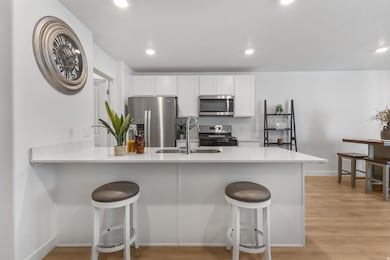 Kitchen featuring a peninsula, white cabinetry, a kitchen breakfast bar, appliances with stainless steel finishes, and recessed lighting