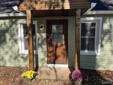 View of exterior entry with a shingled roof and a porch