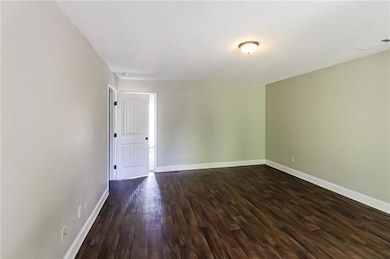 Empty room with dark wood-style flooring and baseboards