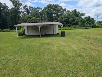 View of green lawn featuring an outdoor structure and a carport