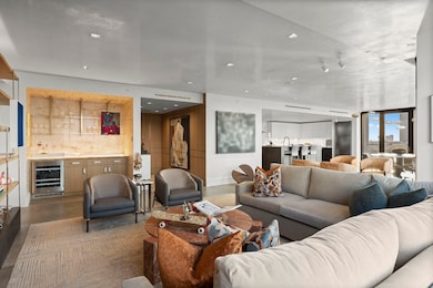 Entertainer's hub: back-lit quartzite bar with custom brass-bracketed shelving, fumed white oak cabinetry.