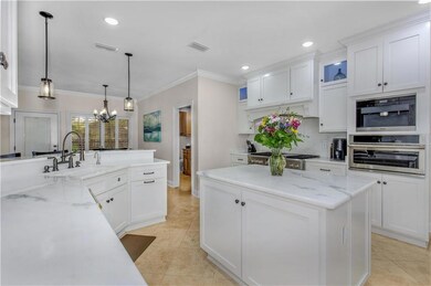 Kitchen with a chandelier, white cabinets, stainless steel gas cooktop, ornamental molding, and light tile patterned flooring