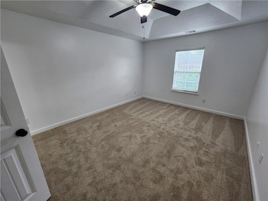 Unfurnished living room featuring carpet floors, ceiling fan, a stone fireplace, a chandelier, and high vaulted ceiling