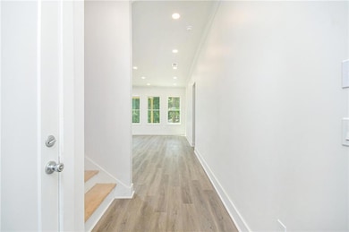 Corridor with light wood-style flooring, recessed lighting, and stairway