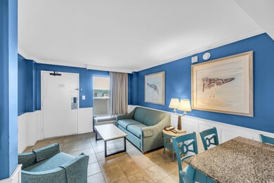 Living area featuring wainscoting, a decorative wall, light tile patterned floors, and crown molding