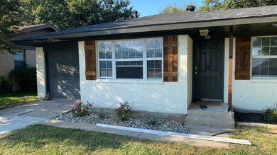 Entrance to property with concrete driveway, brick siding, a shingled roof, and a garage
