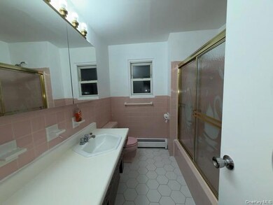 Bathroom featuring tile walls, vanity, light tile patterned floors, a baseboard radiator, and a wainscoted wall