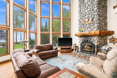 Living area featuring a high ceiling, a stone fireplace, wood finished floors, and baseboards