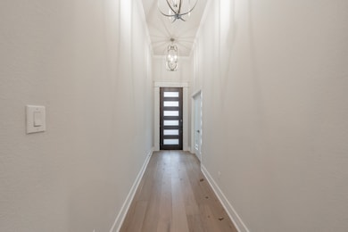 Doorway to outside featuring hardwood / wood-style floors, crown molding, and a chandelier