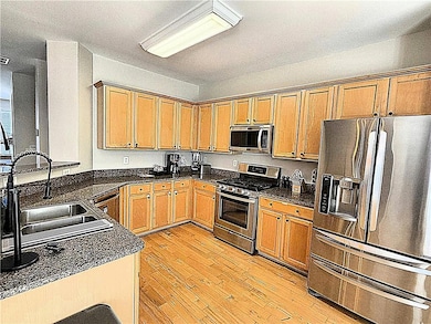 Kitchen with stainless steel appliances, hardwod flooring, dark stone countertops