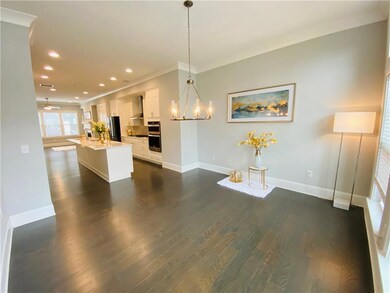 Kitchen with crown molding, white cabinets, baseboards, a kitchen island with sink, and light countertops