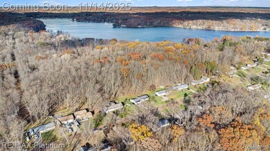 Aerial view of property and surrounding area with a nearby body of water and a forest
