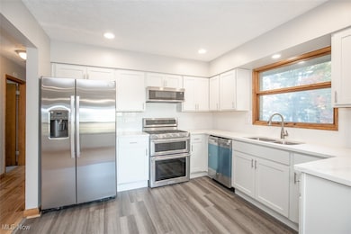 Kitchen with quartz countertops, stainless appliances and white, shaker cabinets