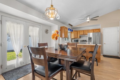 Dining room with lofted ceiling, light wood-style flooring, a chandelier, and a ceiling fan