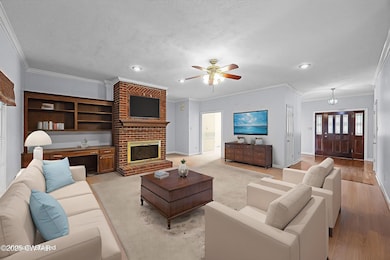 Living room with ornamental molding, recessed lighting, a fireplace, ceiling fan, and light wood-style flooring