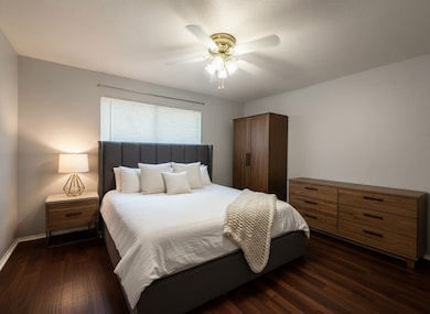 Bedroom with dark wood-style floors, a ceiling fan, and a textured ceiling