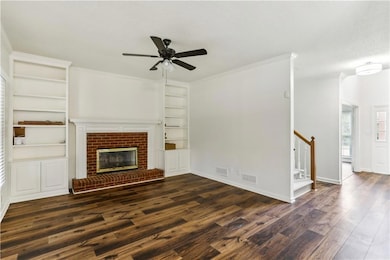 Unfurnished living room featuring ceiling fan, built in shelves, dark wood-style floors, a textured ceiling, and stairway