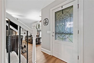 Entryway with wood finished floors, baseboards, and stairway