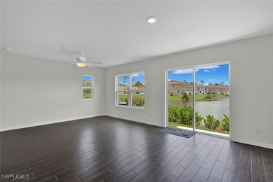 Empty room with dark wood-type flooring, ceiling fan, and a water view