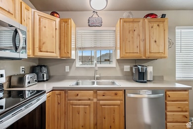 Kitchen with stainless steel appliances, light brown cabinets, and light countertops
