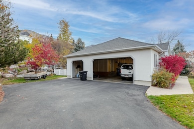 View of side of property with stucco siding, roof with shingles, and asphalt driveway