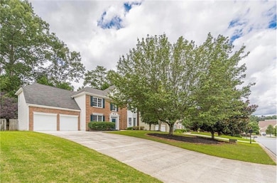 Colonial home with brick siding, a front yard, and concrete driveway