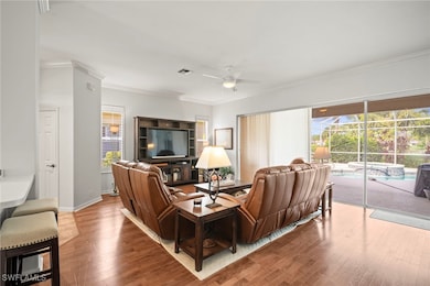 Living room featuring crown molding, wood finished floors, and ceiling fan
