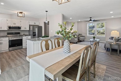 Dining area with recessed lighting, light wood-style flooring, ceiling fan, and a chandelier