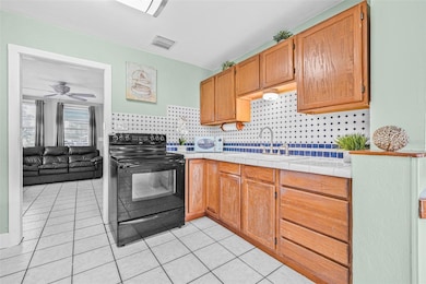 The kitchen area features tile countertops and custom tile backsplash.