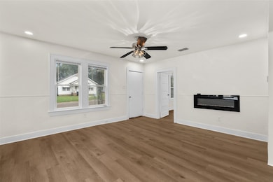 Unfurnished living room featuring recessed lighting, wood finished floors, a ceiling fan, and a glass covered fireplace