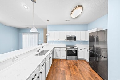 Kitchen featuring white cabinetry, sink, pendant lighting, and appliances with stainless steel finishes