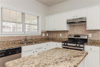 Kitchen with tasteful backsplash, white cabinets, 